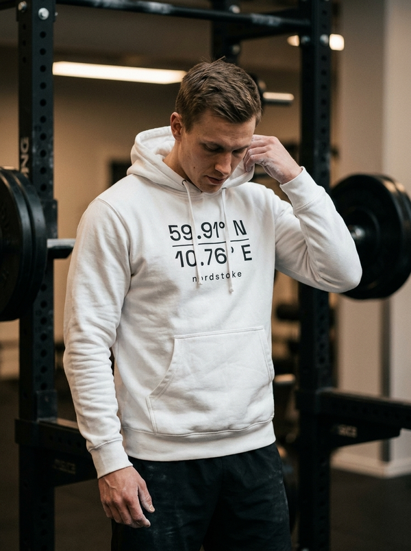 Male hybrid athlete wearing the Nordstoke dark hooded sweatshirt in a gym