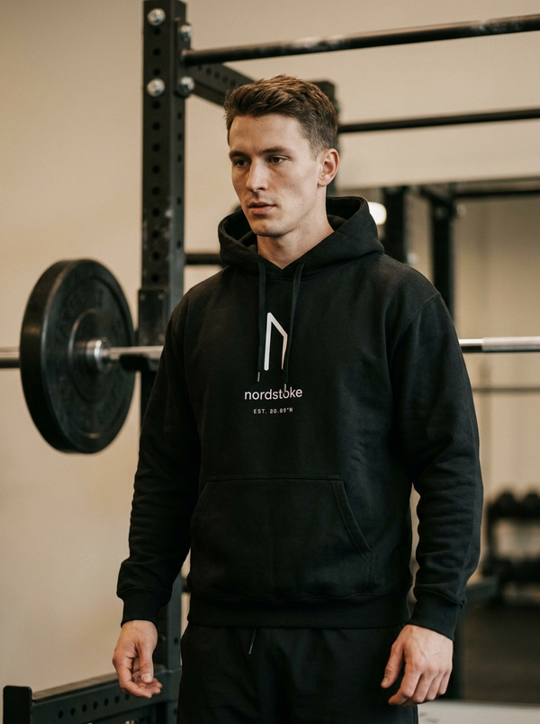 Hybrid athlete wearing the Nordstoke heavyweight hoodie in a dark colourway in a gym