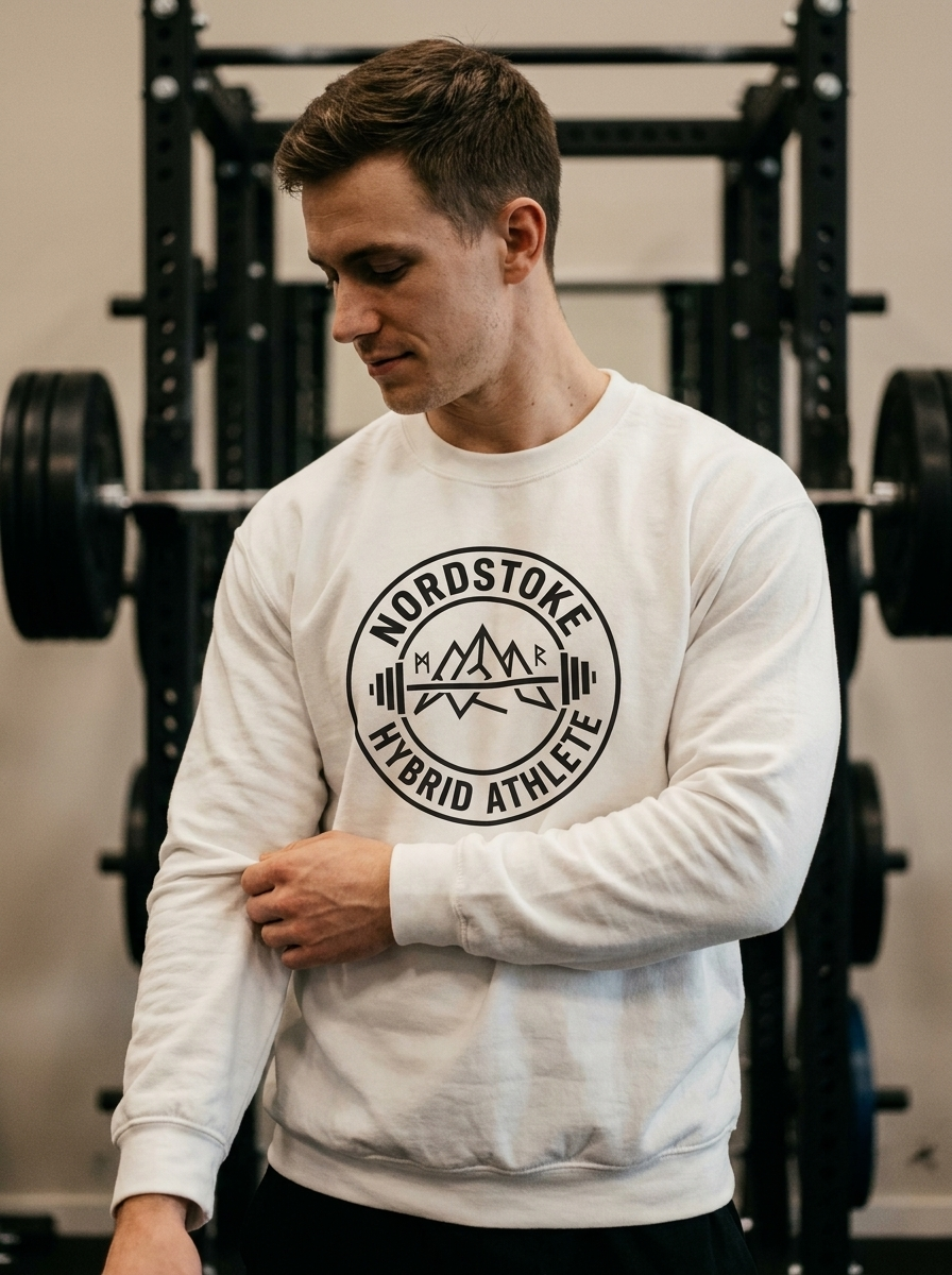 Hybrid athlete wearing the Nordstoke Badge crewneck with Norse barbell emblem in a gym