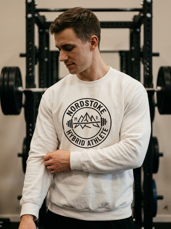 Hybrid athlete wearing the Nordstoke Badge crewneck with Norse barbell emblem in a gym