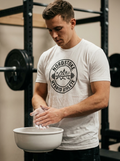 Hybrid athlete wearing the Nordstoke Badge tee with Norse barbell emblem in a gym