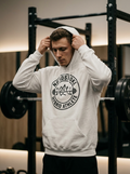 Hybrid athlete wearing the Nordstoke Badge hoodie with Norse barbell emblem in a gym