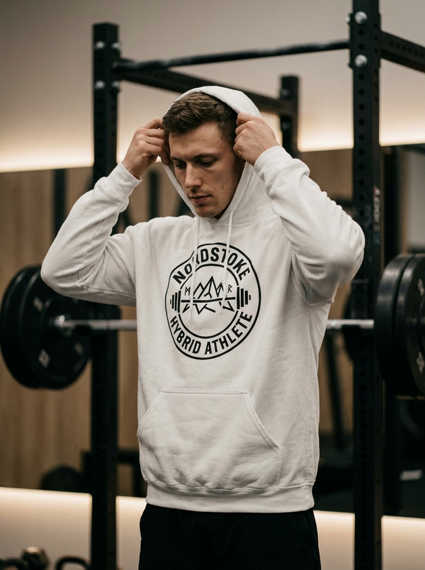 Hybrid athlete wearing the Nordstoke Badge hoodie with Norse barbell emblem in a gym