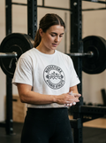 Female hybrid athlete wearing the Nordstoke Badge crop tee in a gym