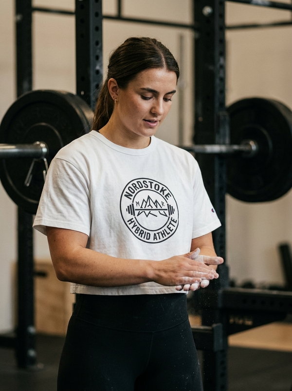 Female hybrid athlete wearing the Nordstoke Badge crop tee in a gym